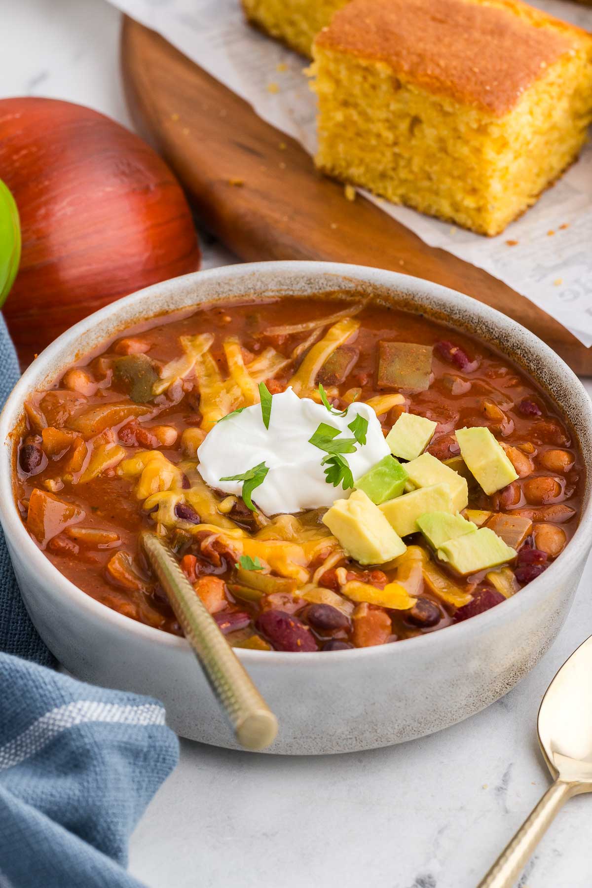 bowl of 5 Bean Chili with garnishes and cornbread in the background