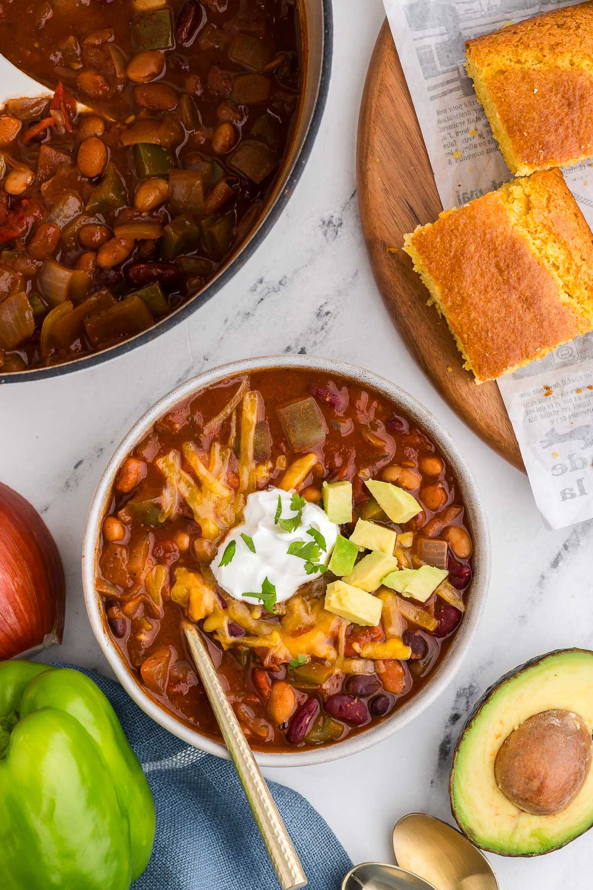 top view of 5 Bean Chili with cornbread and avocado in the background