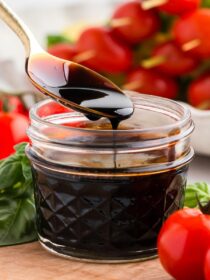 a spoon scooping balsamic glaze out of a jar