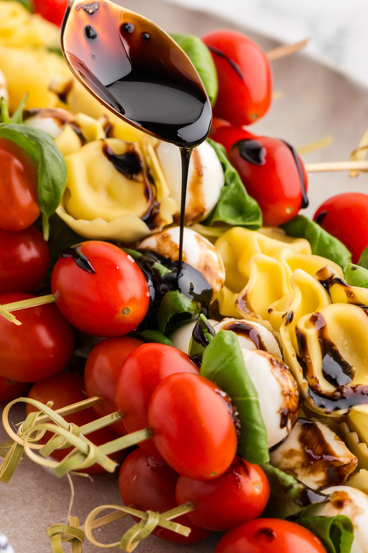 drizzling balsamic glaze on tortellini skewers