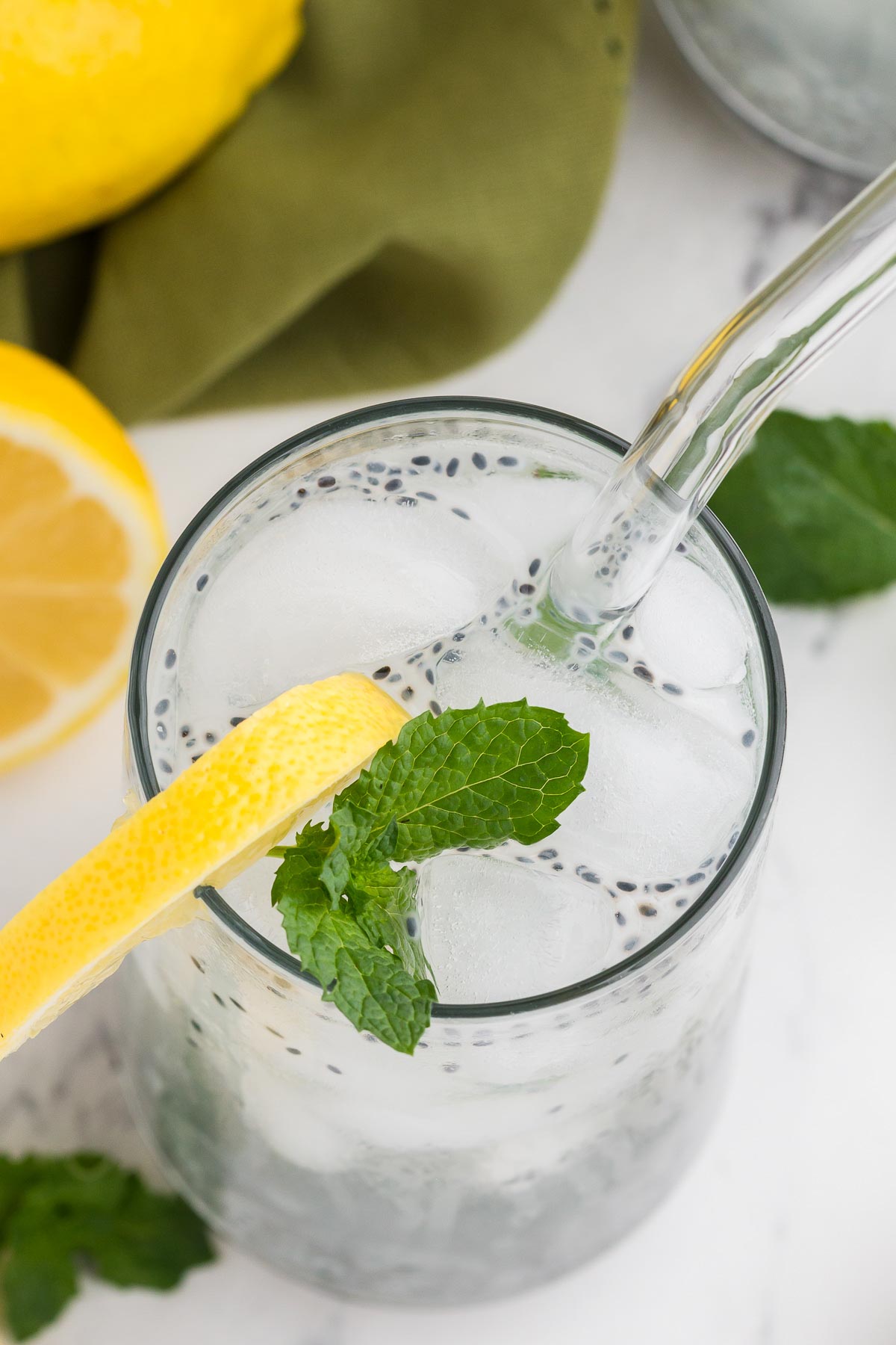 top view of basil seed drink with lemon, mint, and glass straw