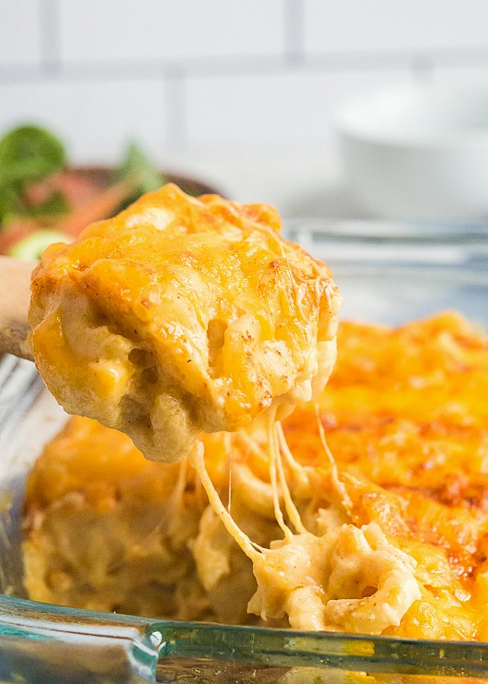 Scooping a big cheesy portion of the best baked macaroni and cheese recipe ever