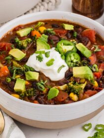 A bowl full of Black Bean Veggie Chili with a gold spoon on a napkin
