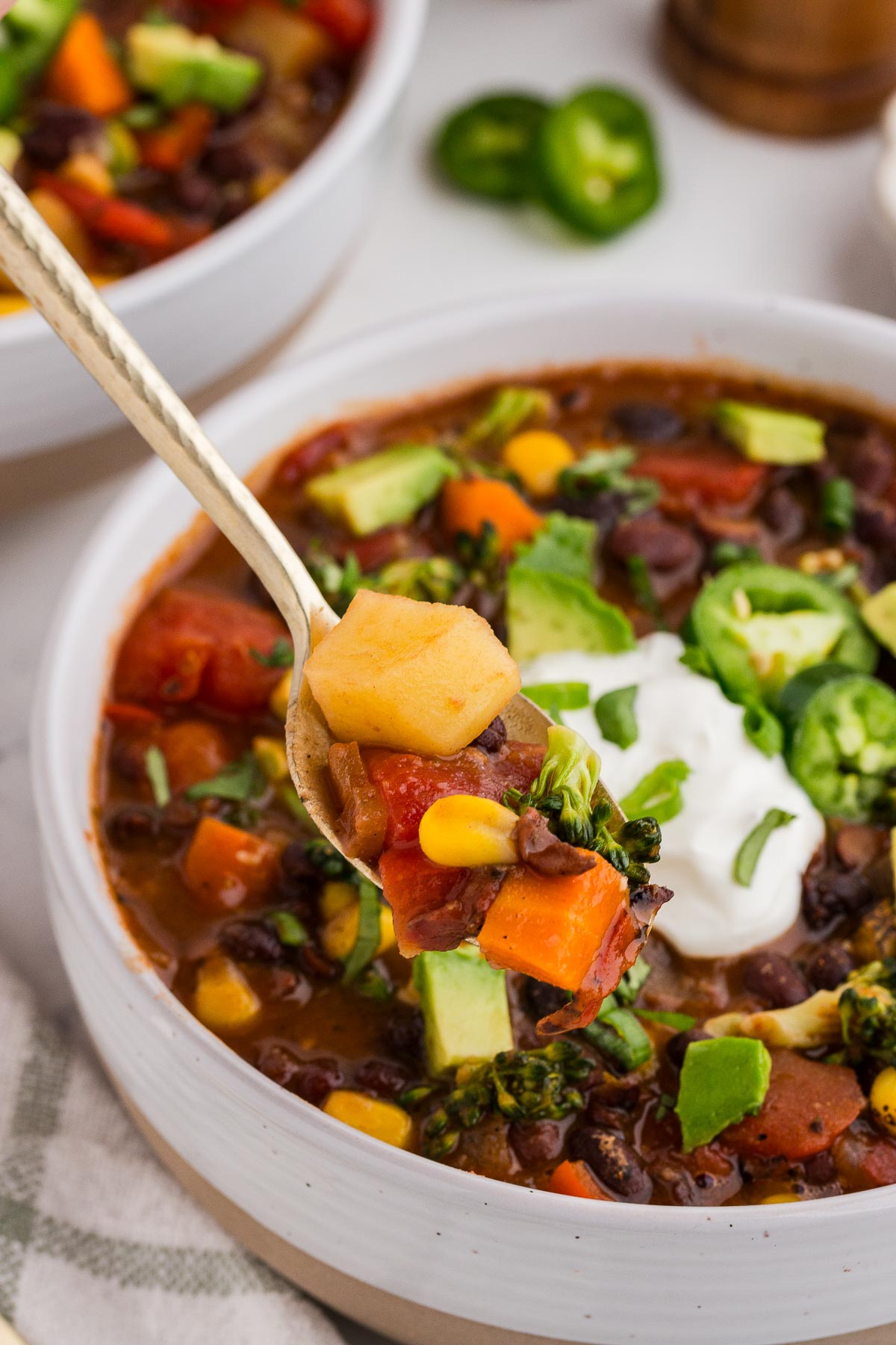 A spoon lifts out a bite of Black Bean Veggie Chili from the bowl