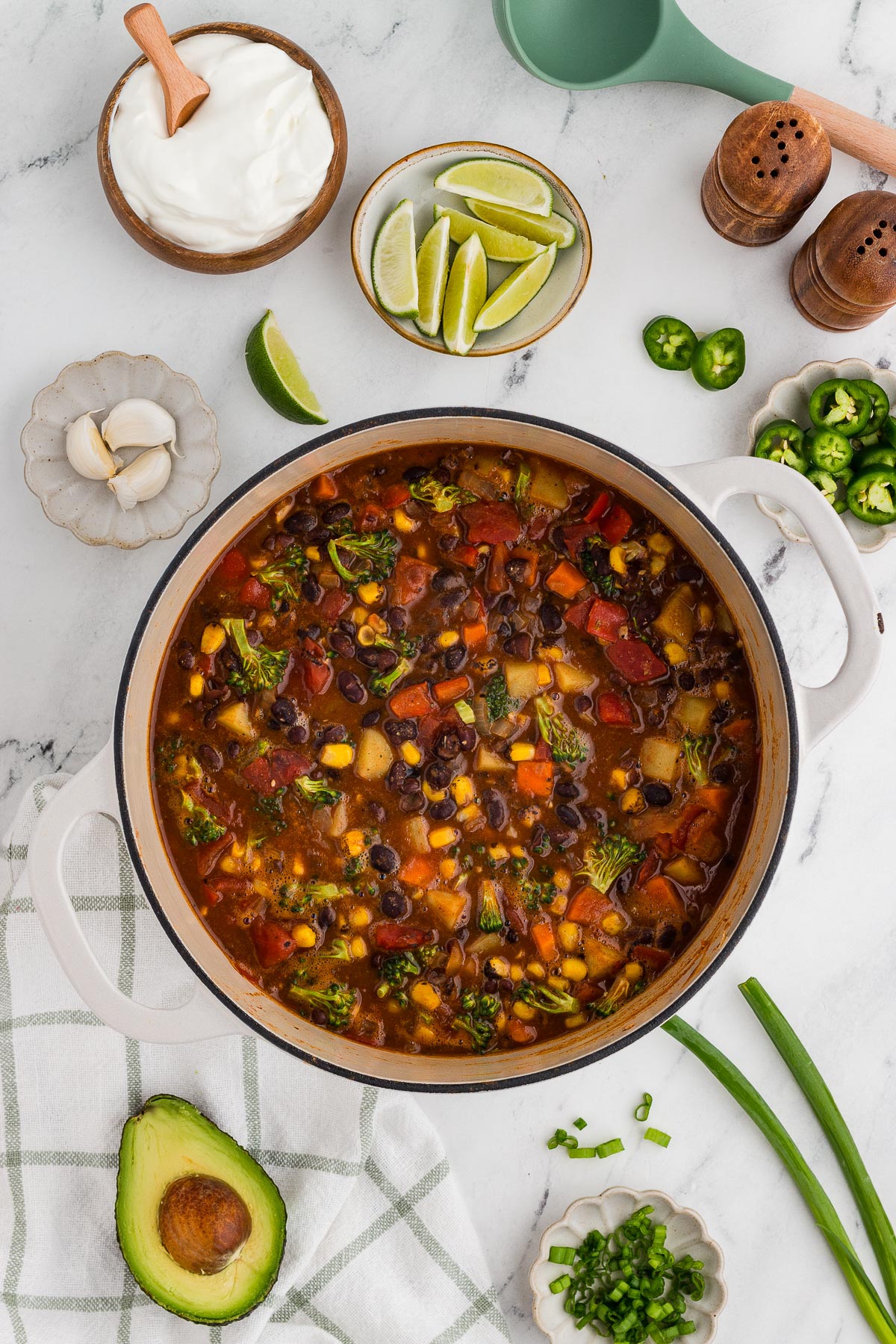 Top view of a pot of black bean veggie chili. A windowpane plaid napkin is in the background