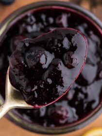 A spoon scooping blueberry sauce out of a jar