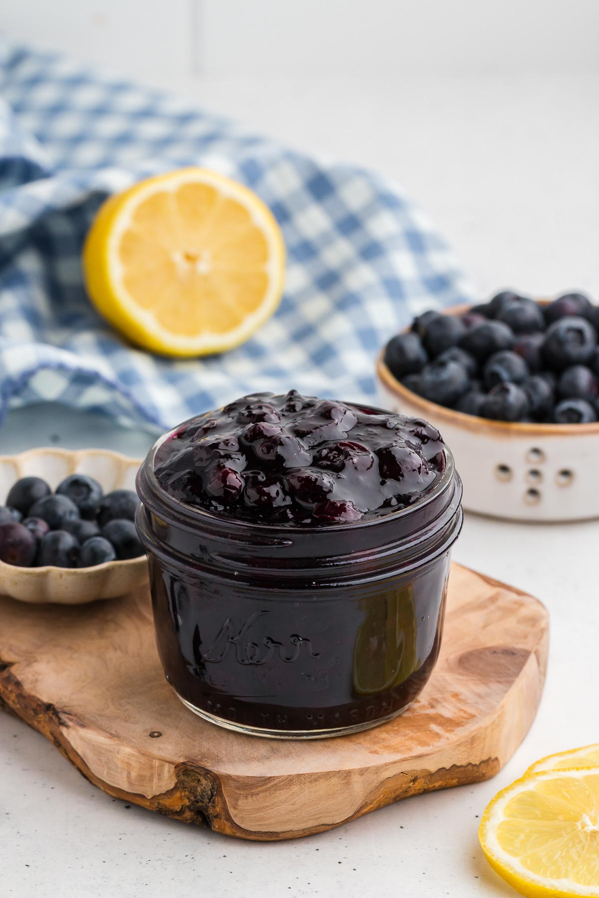 A mason jar full of blueberry sauce on an organic piece of wood