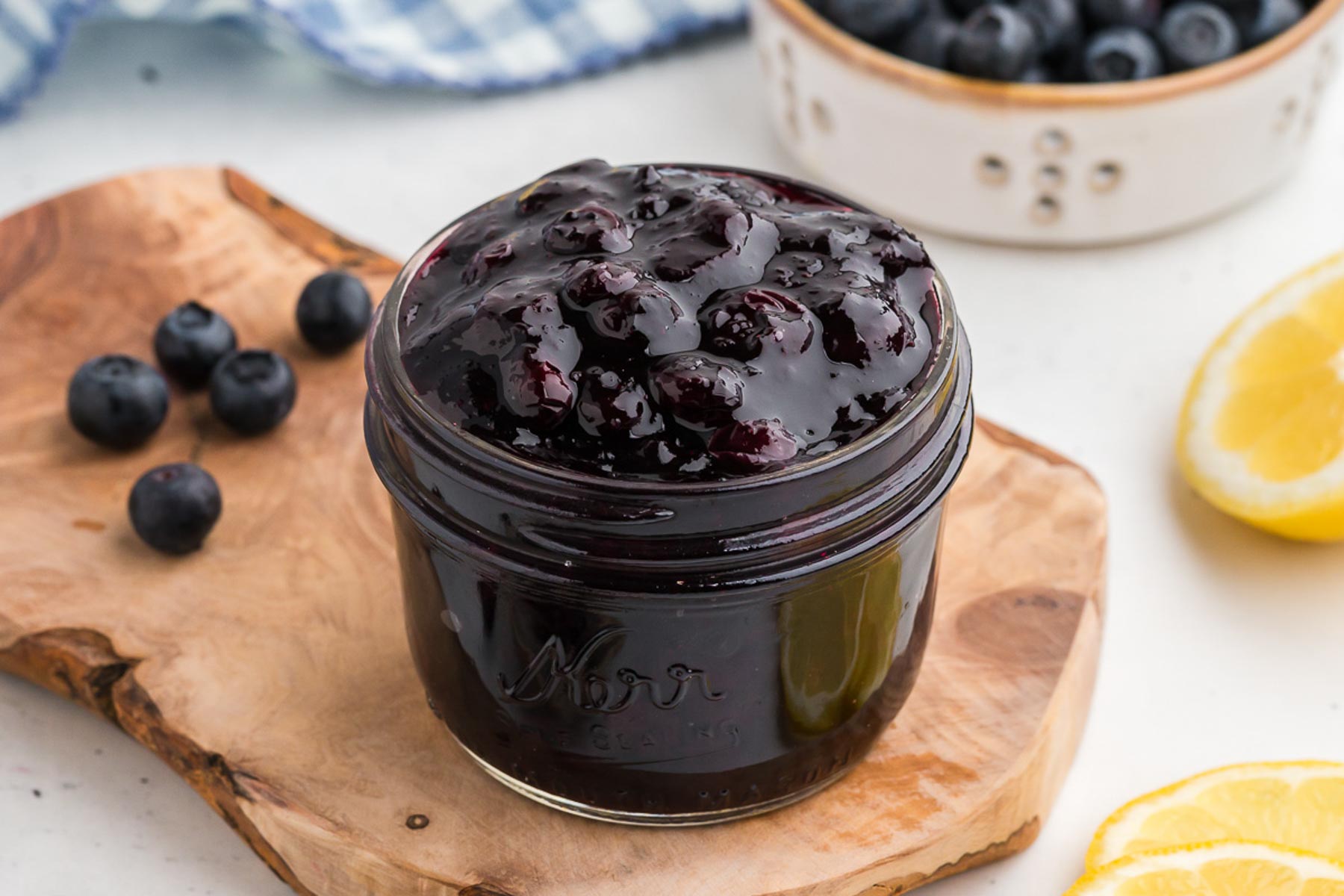 A mason jar full of blueberry sauce on an organic piece of wood