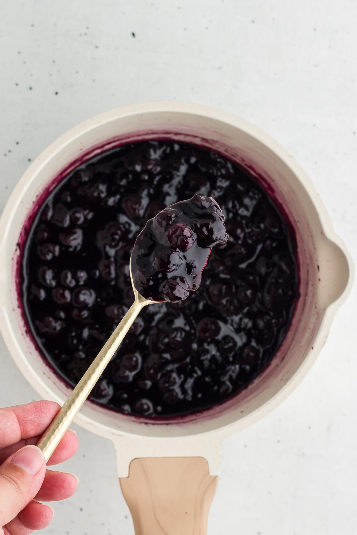 Thick blueberry sauce finished cooking in a white saucepan