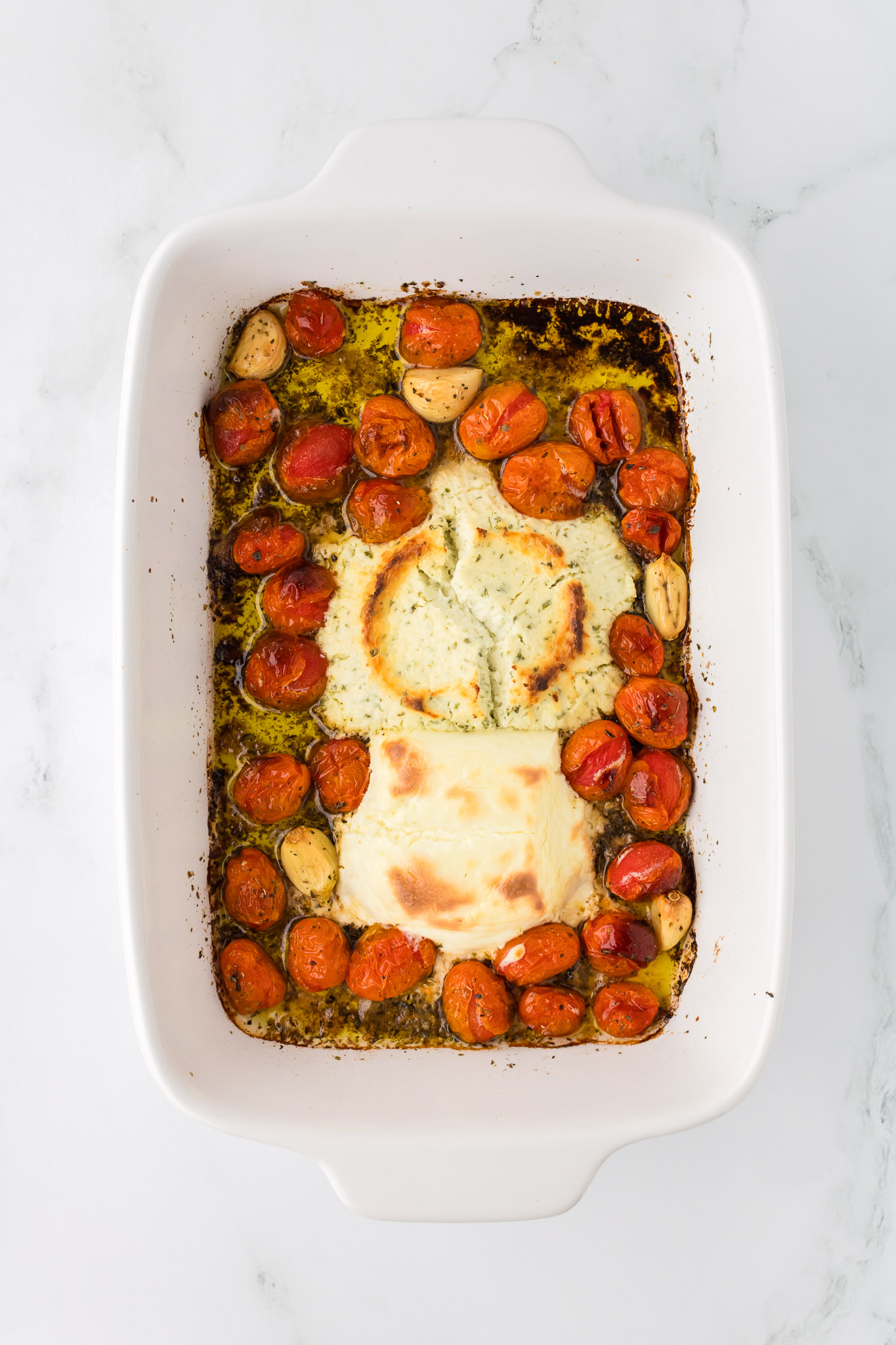 A baking dish full of melty Boursin and cream cheeses plus tomatoes and garlic for Baked Boursin Pasta
