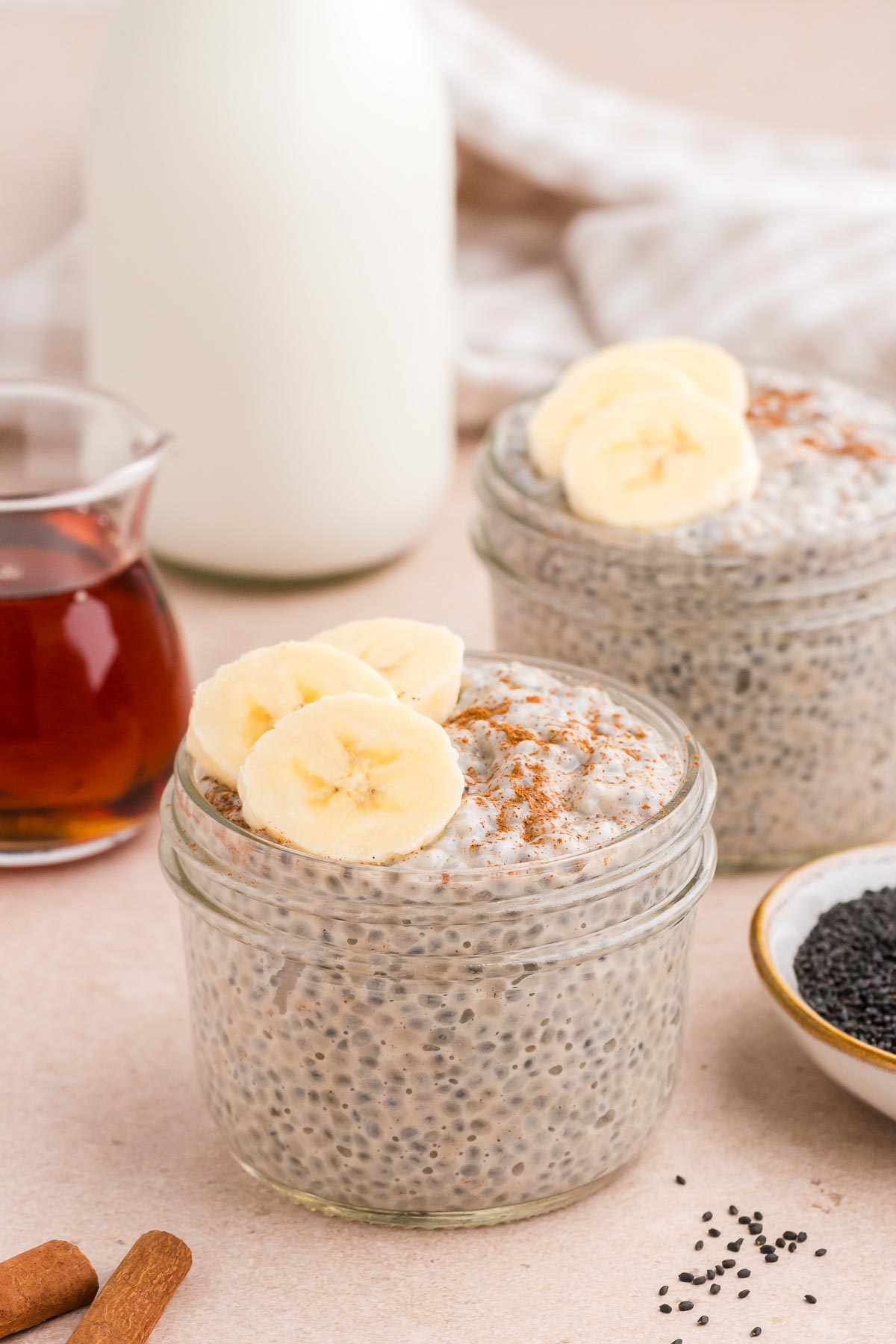 Chai Latte Basil Seed Pudding in small mason jars with cinnamon and sliced bananas