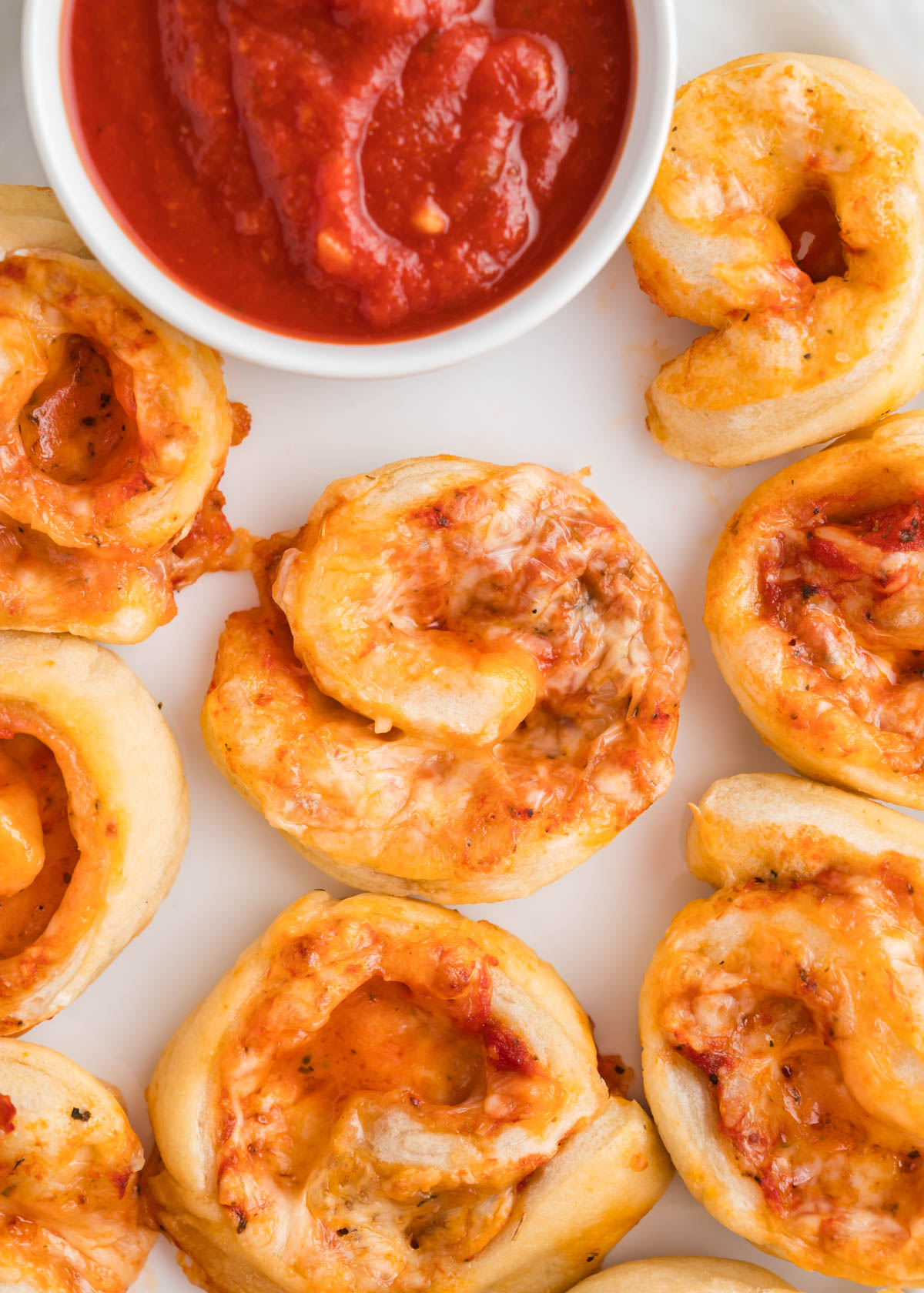 Pizza dough smeared with pizza sauce ready to roll into pizza pinwheels