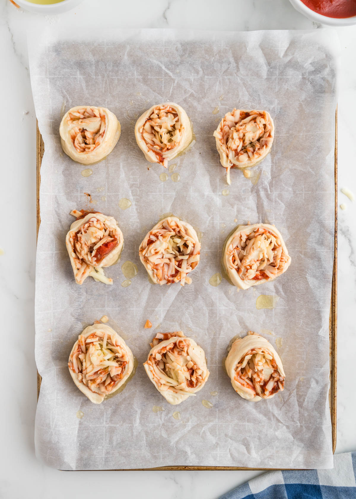 Pizza pinwheels on a baking sheet ready to go into the oven.