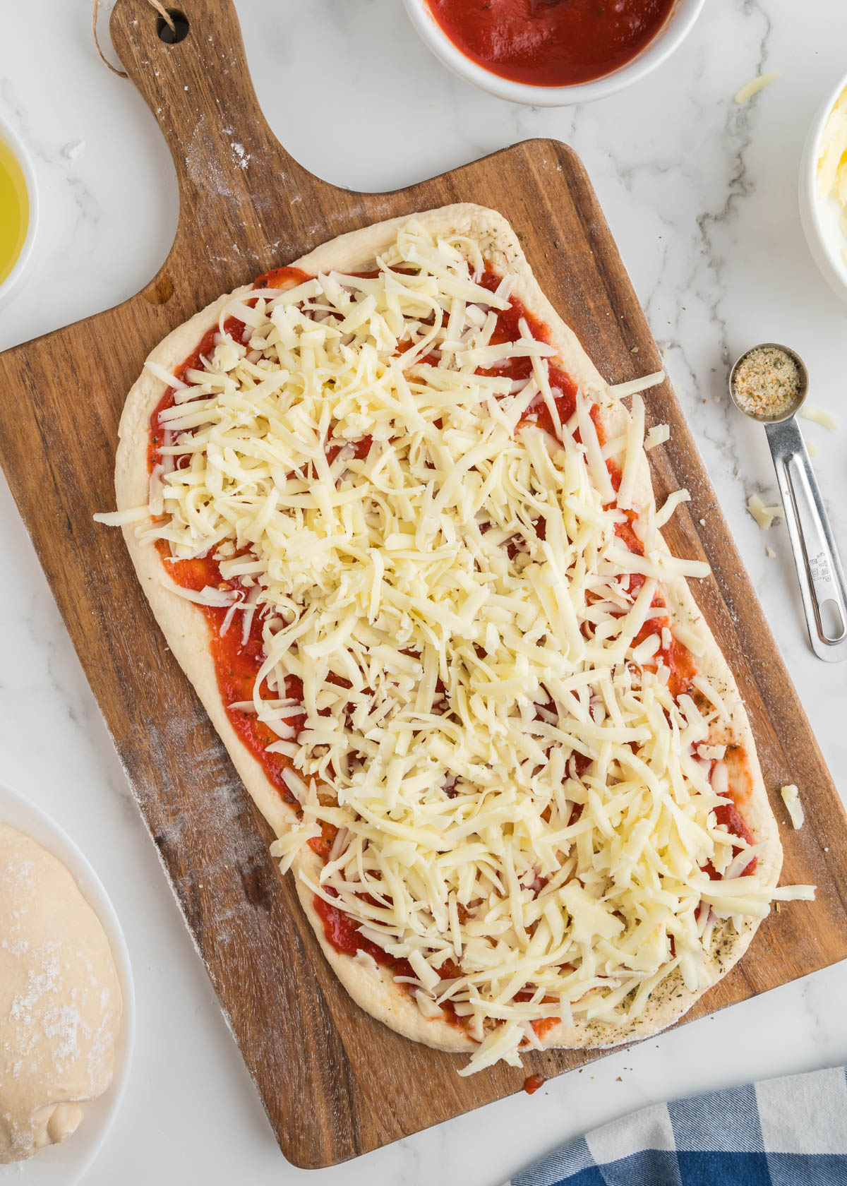 Pizza dough smeared with pizza sauce and covered in mozzarella ready to roll into pizza pinwheels