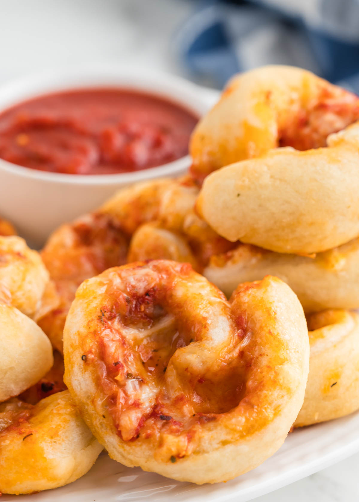 A white platter with pizza pinwheels ready to serve