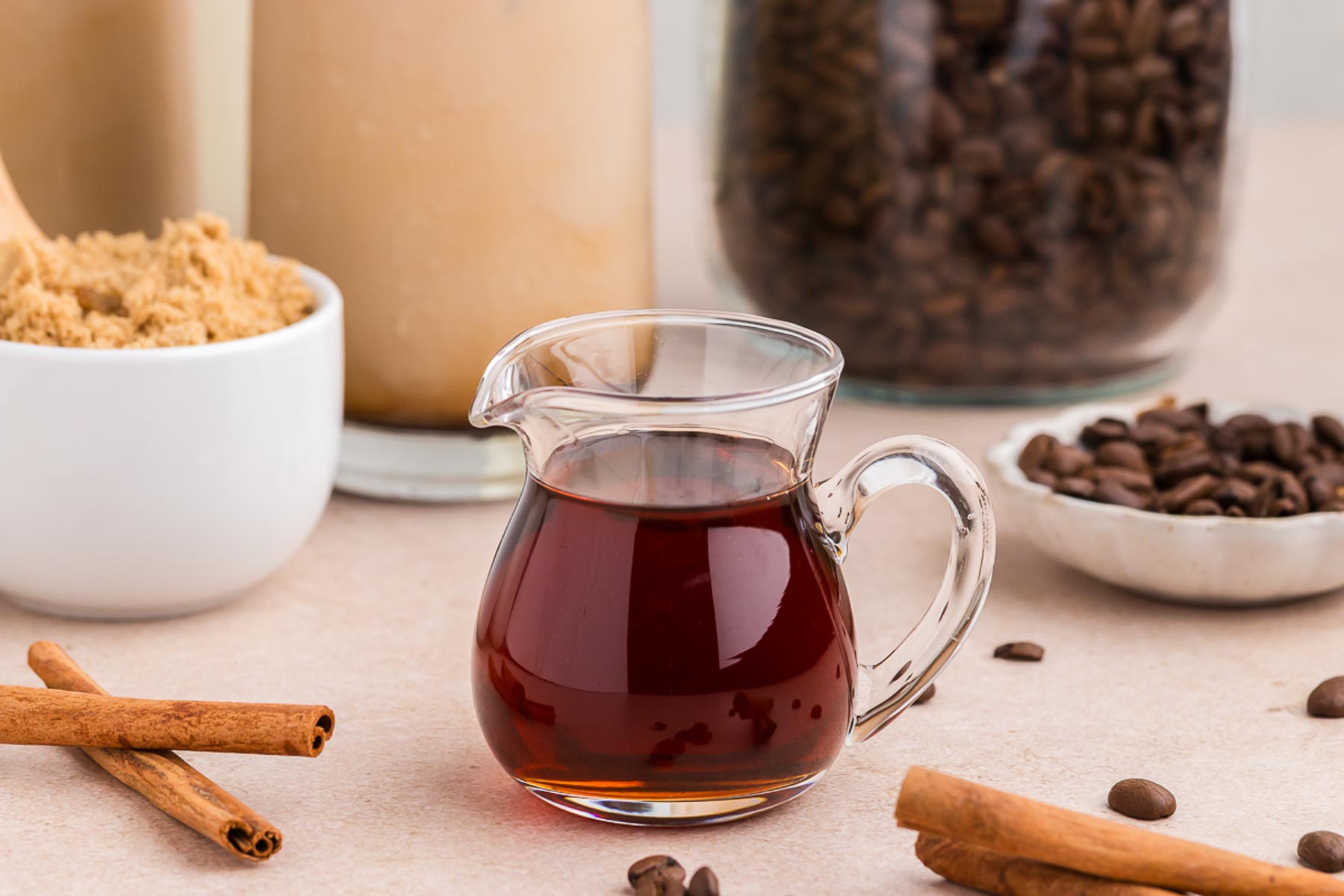 Cinnamon Dolce Coffee Syrup in a pitcher with cinnamon sticks