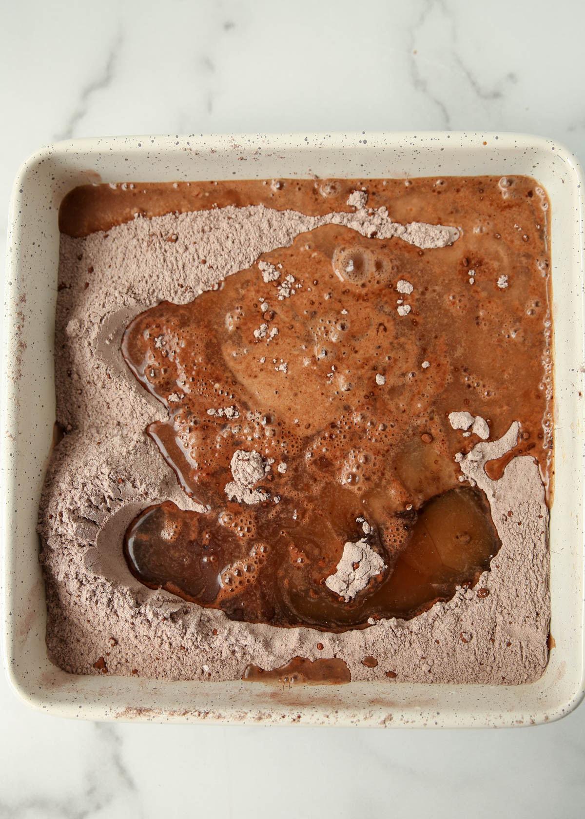 Wet ingredients for chocolate wacky cake have been poured over the dry; now it's ready to mix.