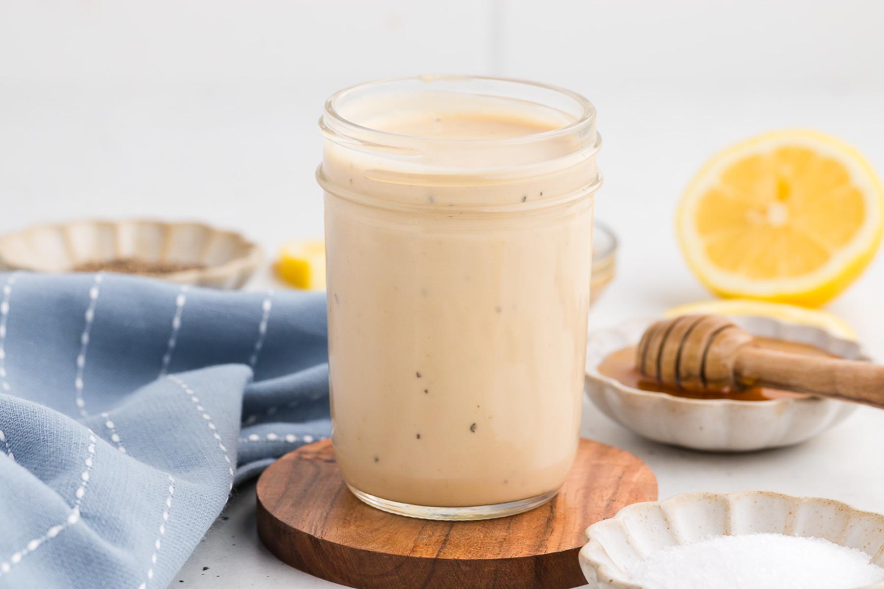 Creamy Lemon Tahini Dressing in a jar on a wooden coaster