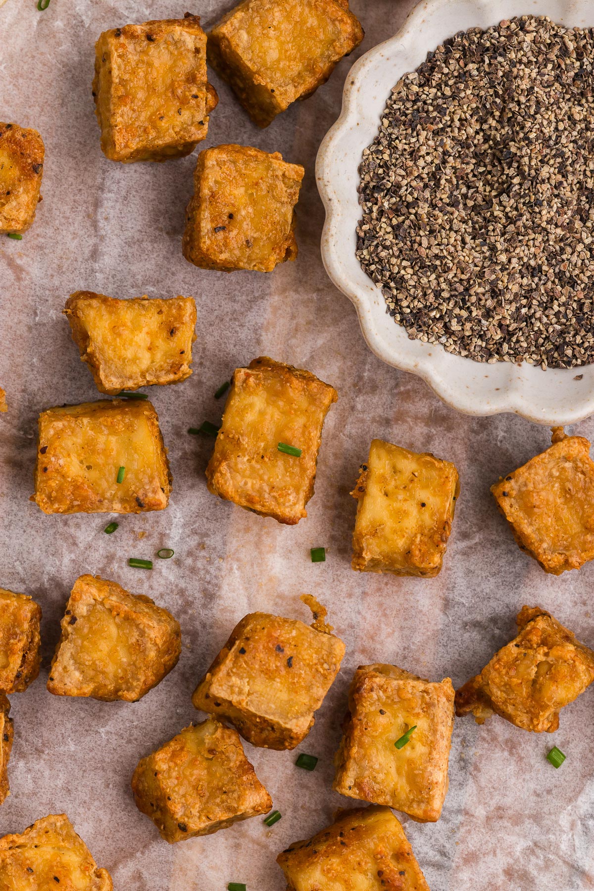 Crispy Air Fryer Tofu with a dish of ground black pepper in the background