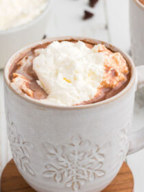 crock pot hot cocoa in a white mug with whipped cream on top