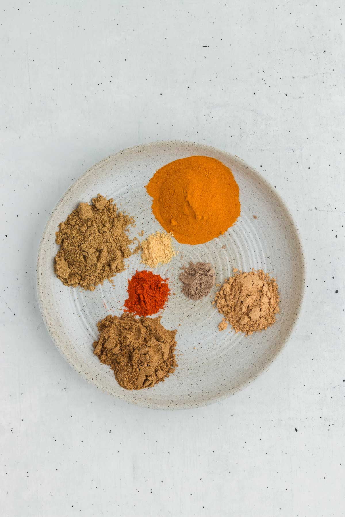 ingredients for homemade curry powder on a stoneware plate