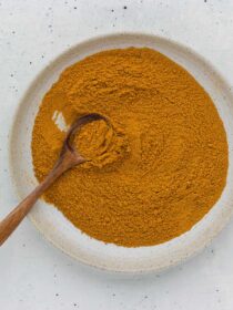 a bowl full of homemade curry powder mix with a wooden spoon