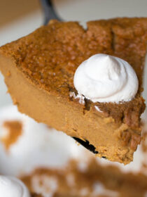 A slice of dairy-free impossible pumpkin pie is lifted out of the pie plate.