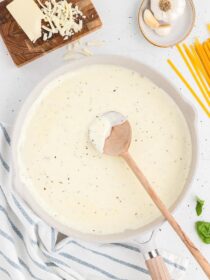 homemade alfredo sauce in a skillet with a wooden spoon