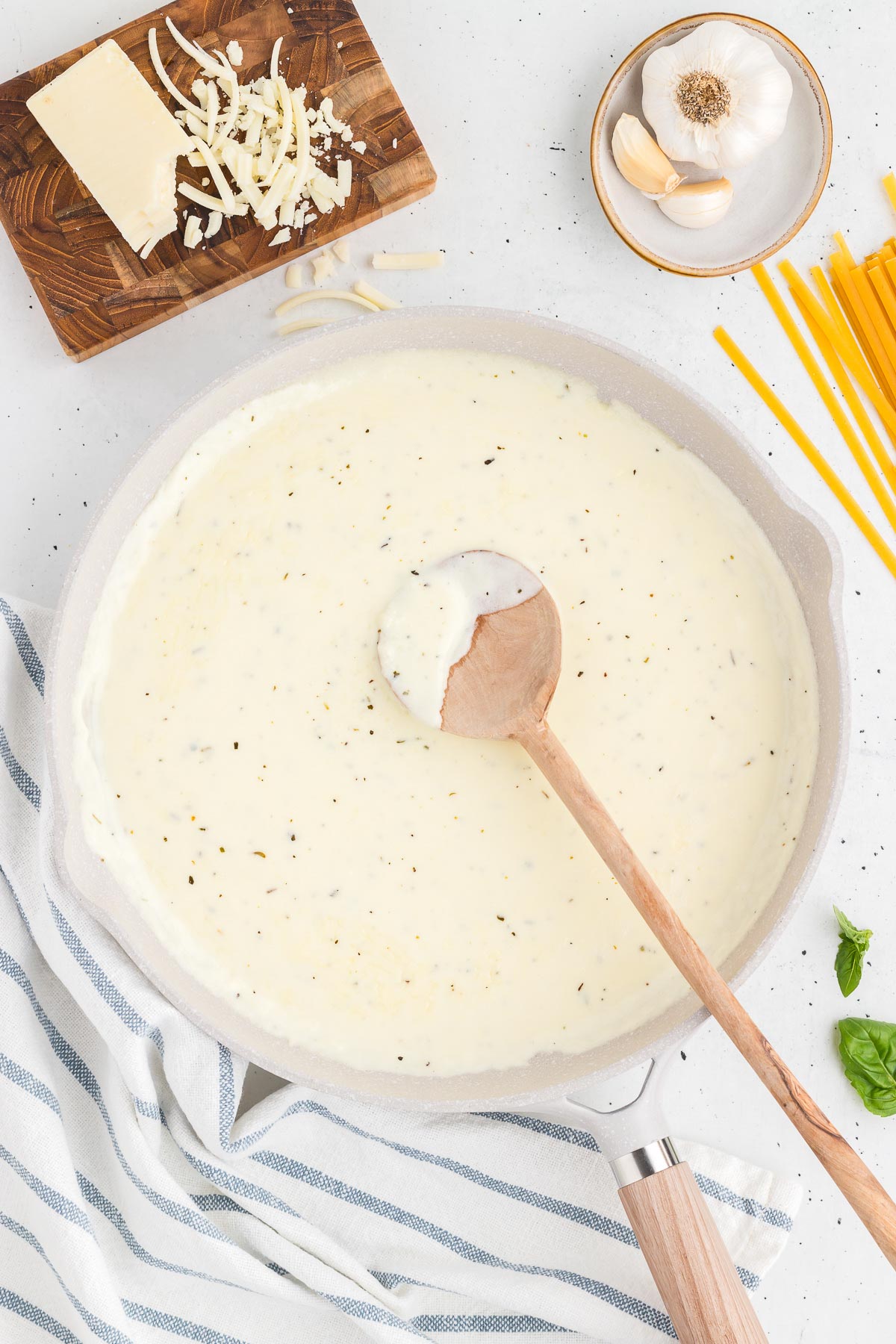 homemade alfredo sauce in a skillet with a wooden spoon