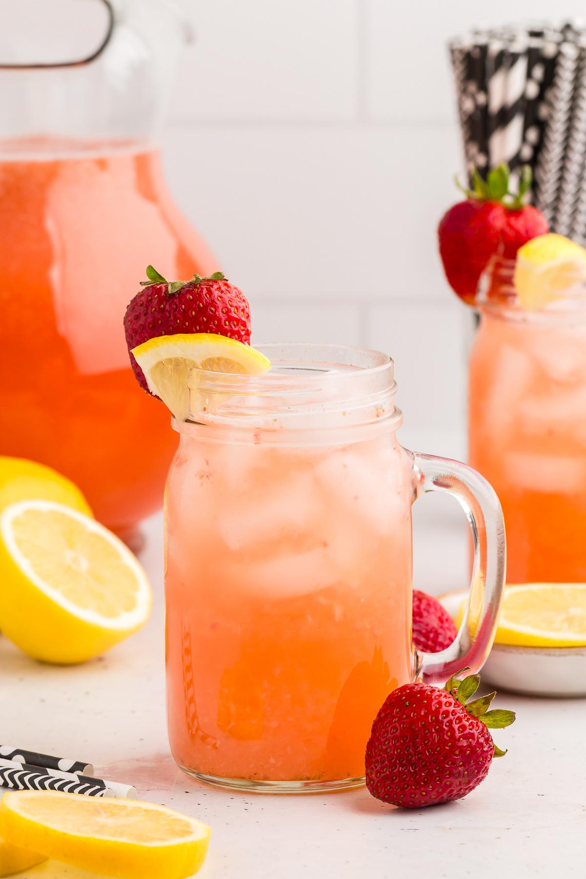 Easy Strawberry Lemonade in a glass with a pitcher in the background