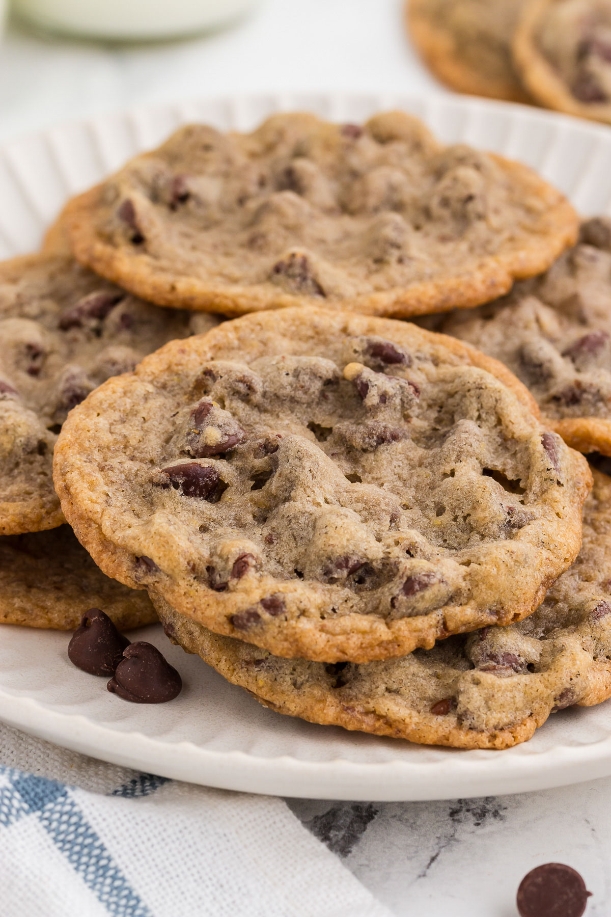 A close-up of a pile Eggless Chocolate Chip Cookies on a white plate.