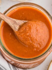 A wood spoon scoops out some Homemade Enchilada Sauce