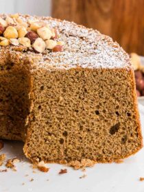 Hazelnut cake sliced in half with hazelnut garnish and dusting of powdered sugar