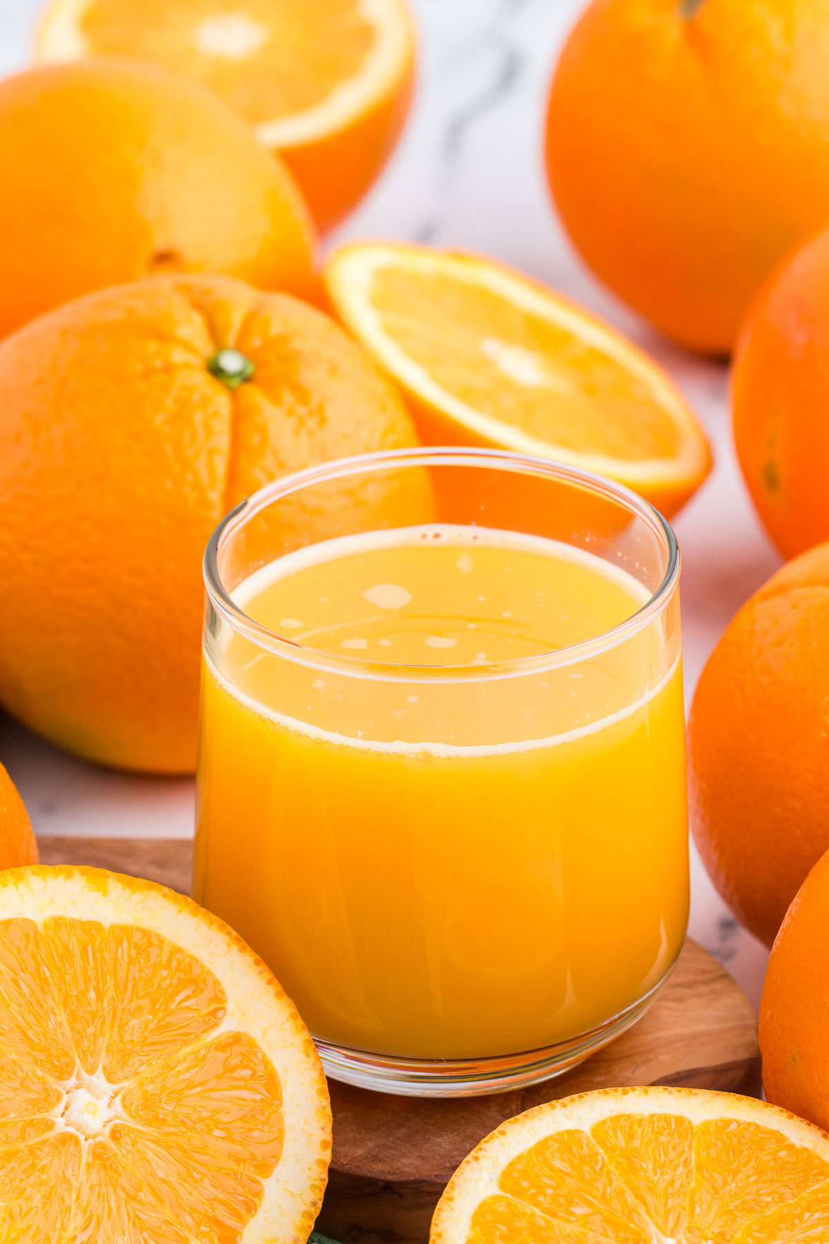 A glass of refreshing orange juice with naval oranges all around