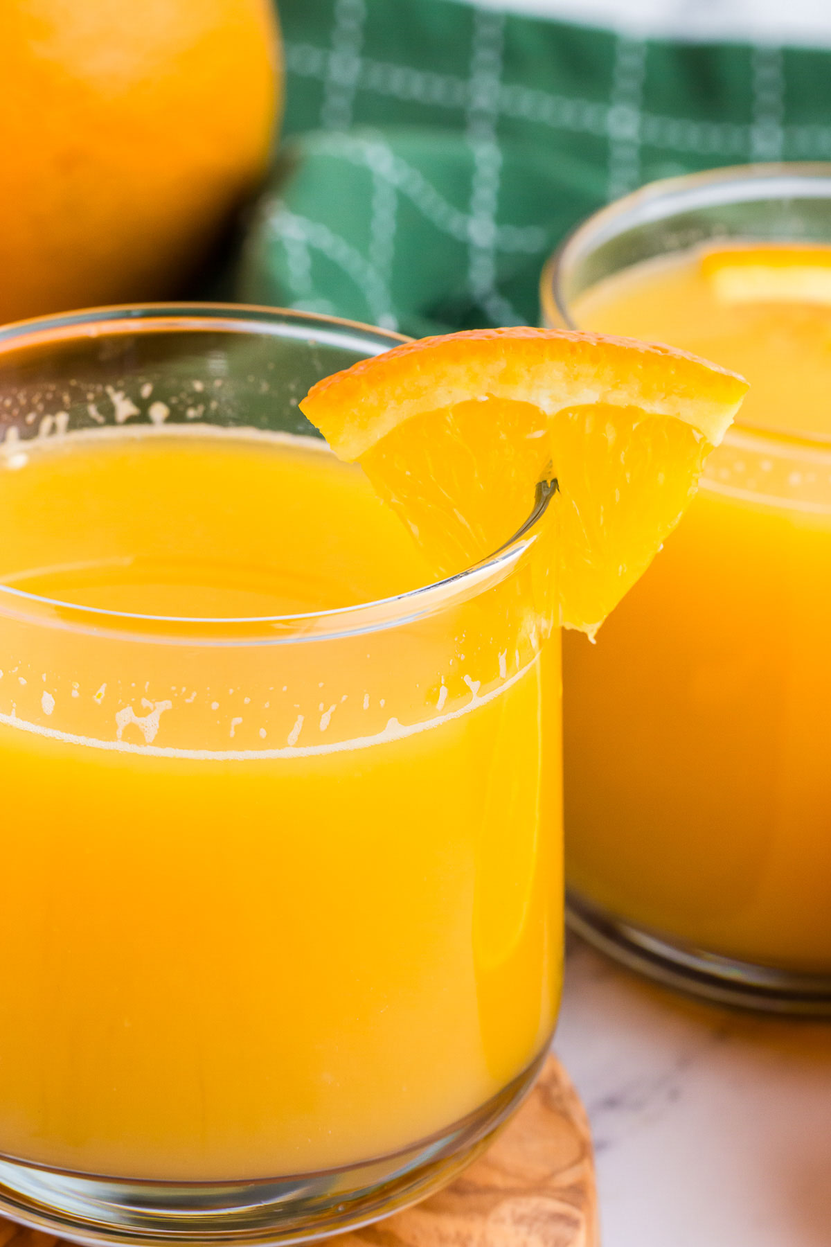 A glass of orange juice with an orange wedge on the rim