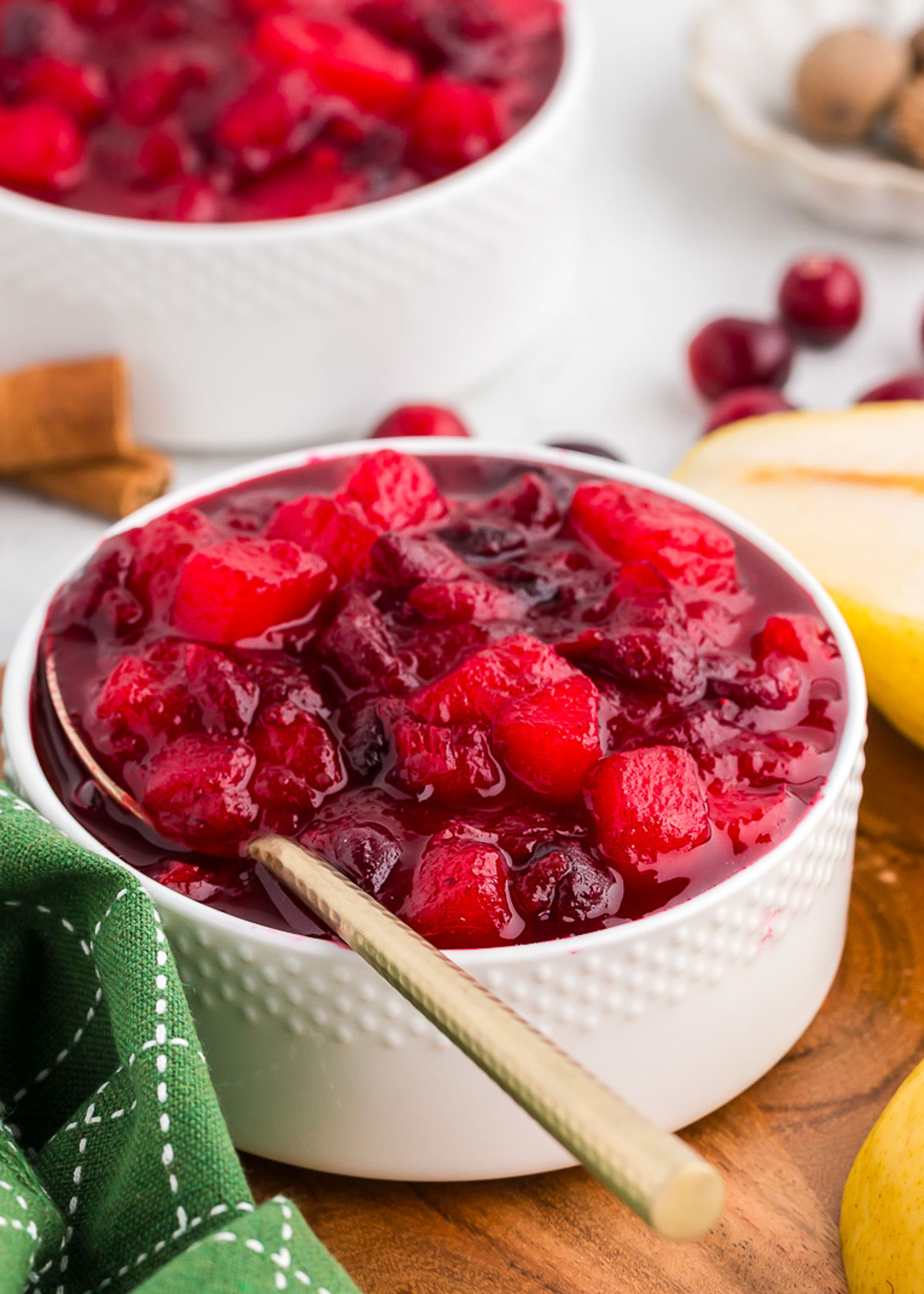ginger pear cranberry sauce in a white bowl with a gold spoon