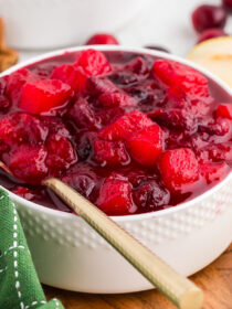 ginger pear cranberry sauce in a white bowl with a gold spoon