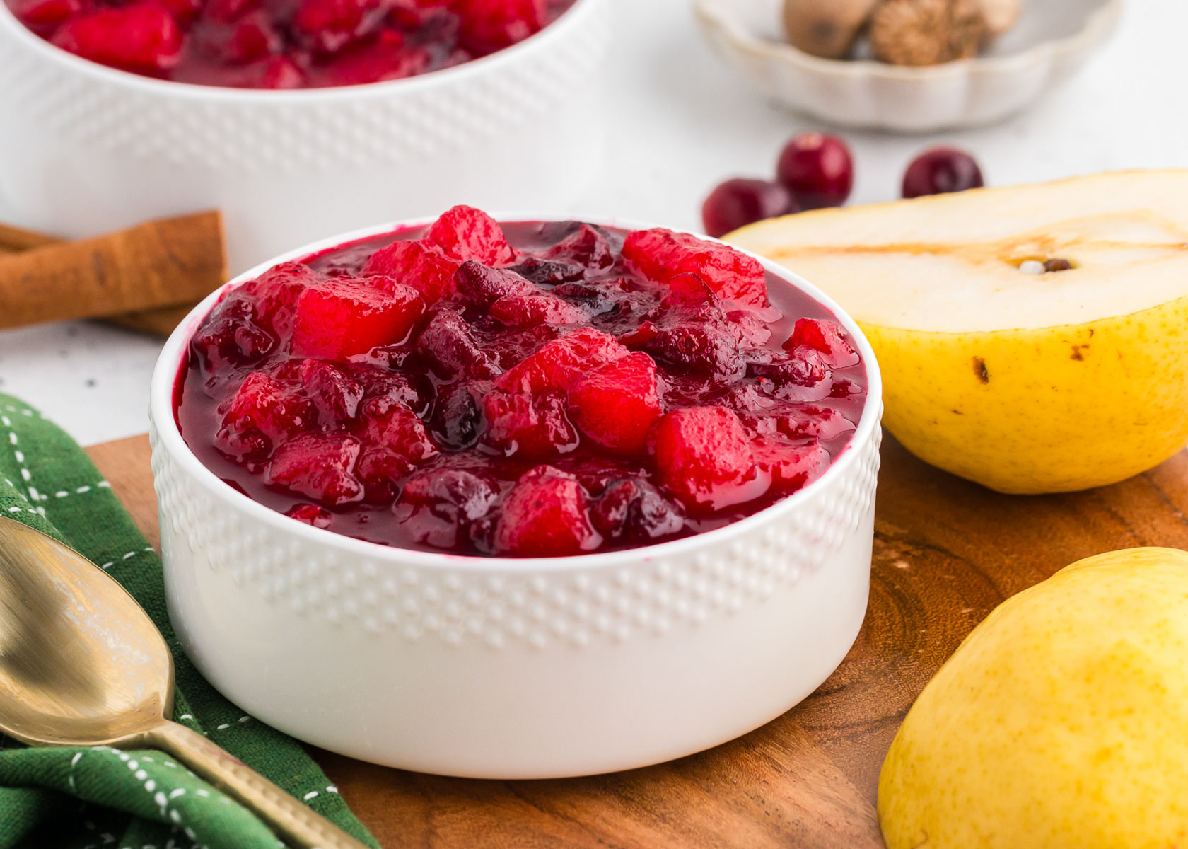 ginger pear cranberry sauce in a white bowl with pears and cranberries in the background