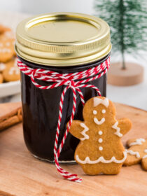 Jar of gingerbread coffee syrup with red and white baker's twine and a gingerbread cookie
