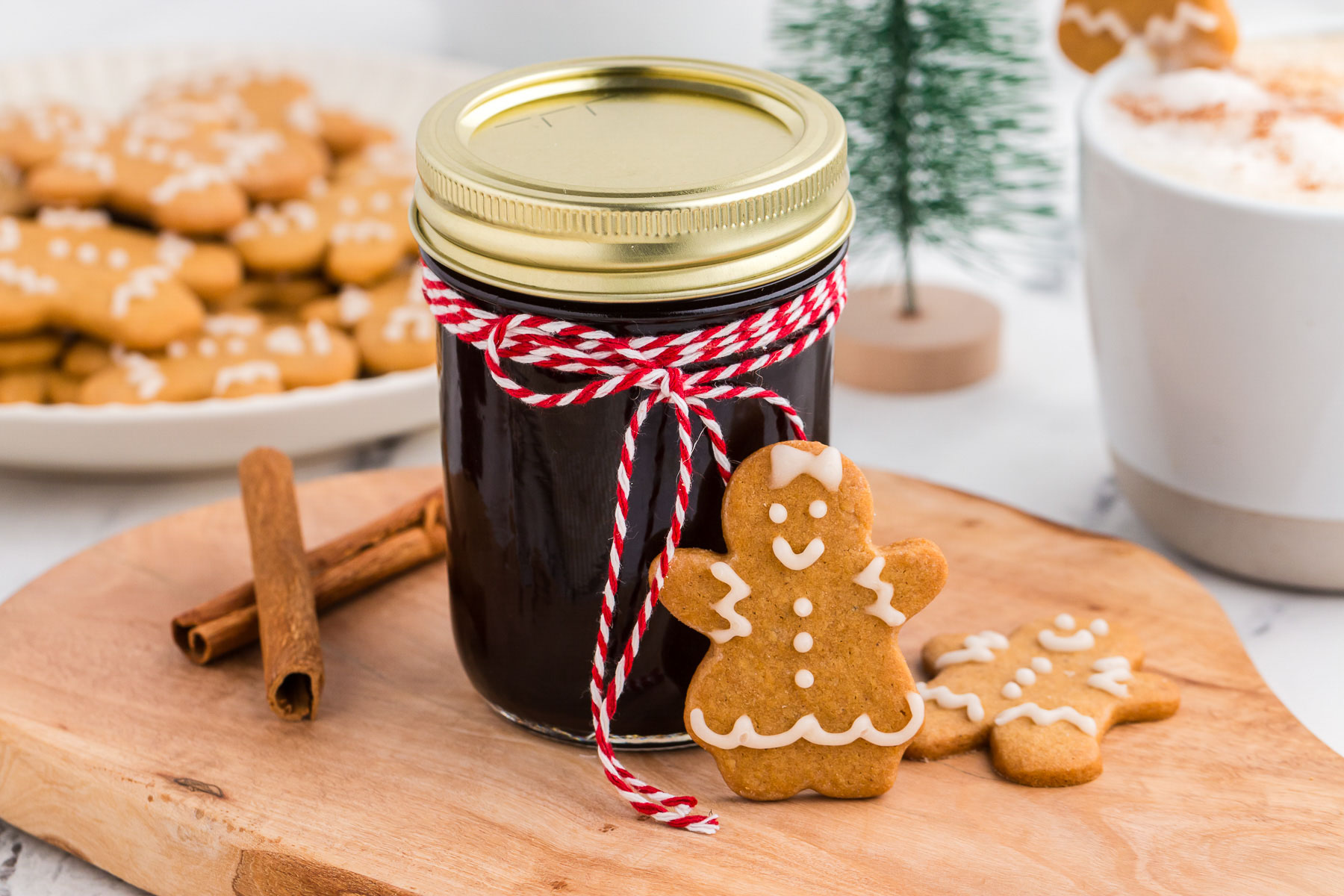 Jar of gingerbread coffee syrup with red and white baker's twine and a gingerbread cookie