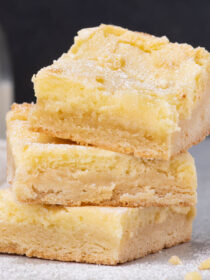 Three squares of gooey butter cake in a pile with a black and white background.