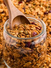A jar full of Homemade Granola with a wooden scoop