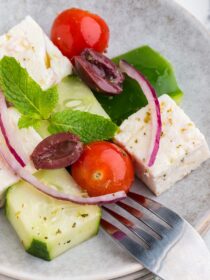 A silver fork with a plate full of Greek Mosaic Salad