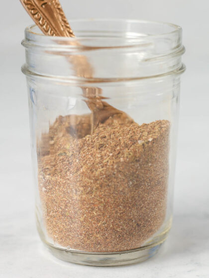 A jar of homemade taco seasoning with a measuring spoon inside it.
