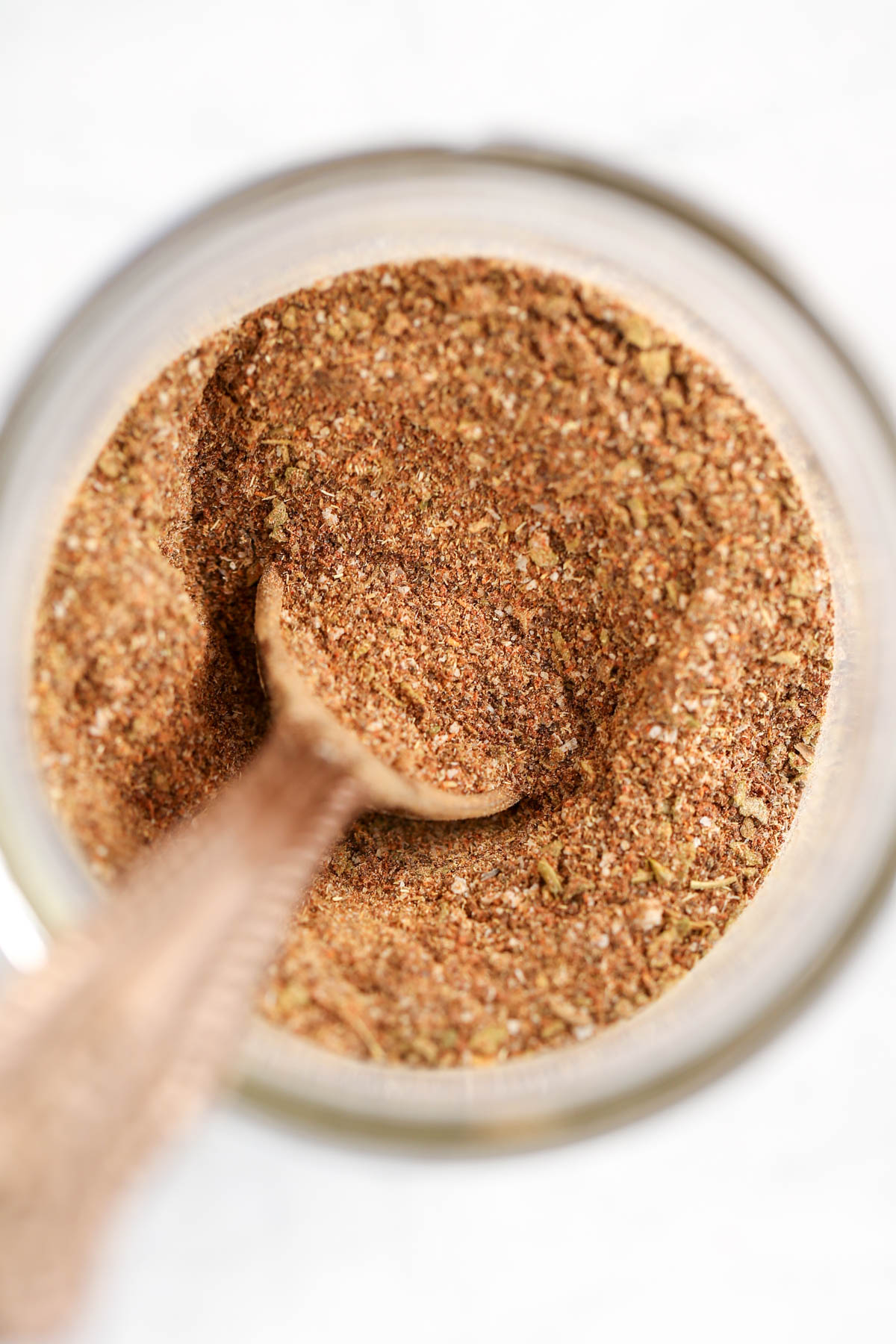 A jar of homemade taco seasoning with a measuring spoon inside it.