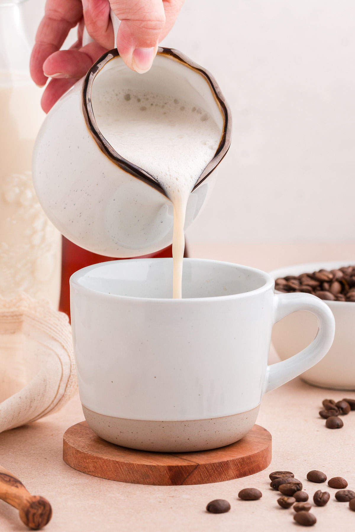 pouring frothy oat milk into a mug full of oat milk latte