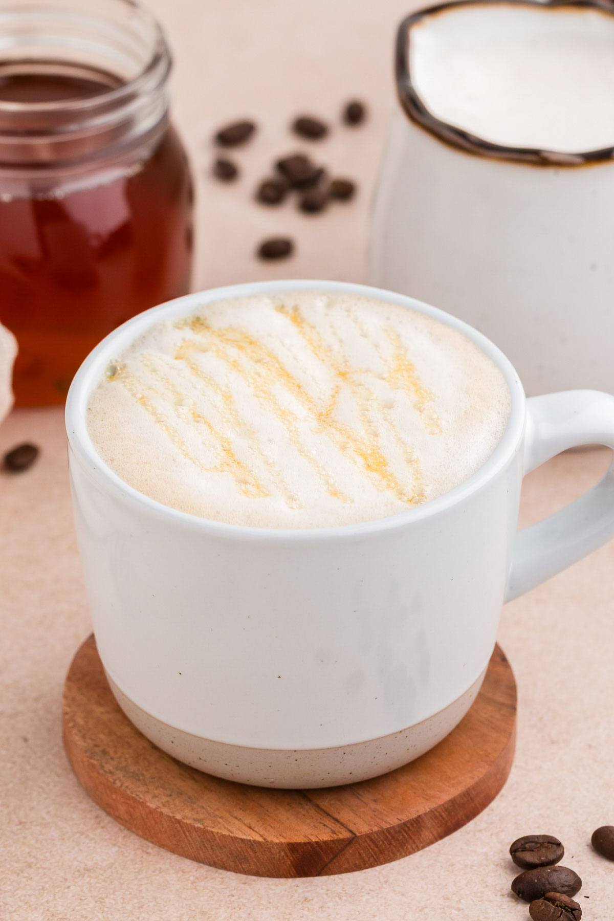 A white stoneware cup with an oat milk latte with honey drizzled over the foam.