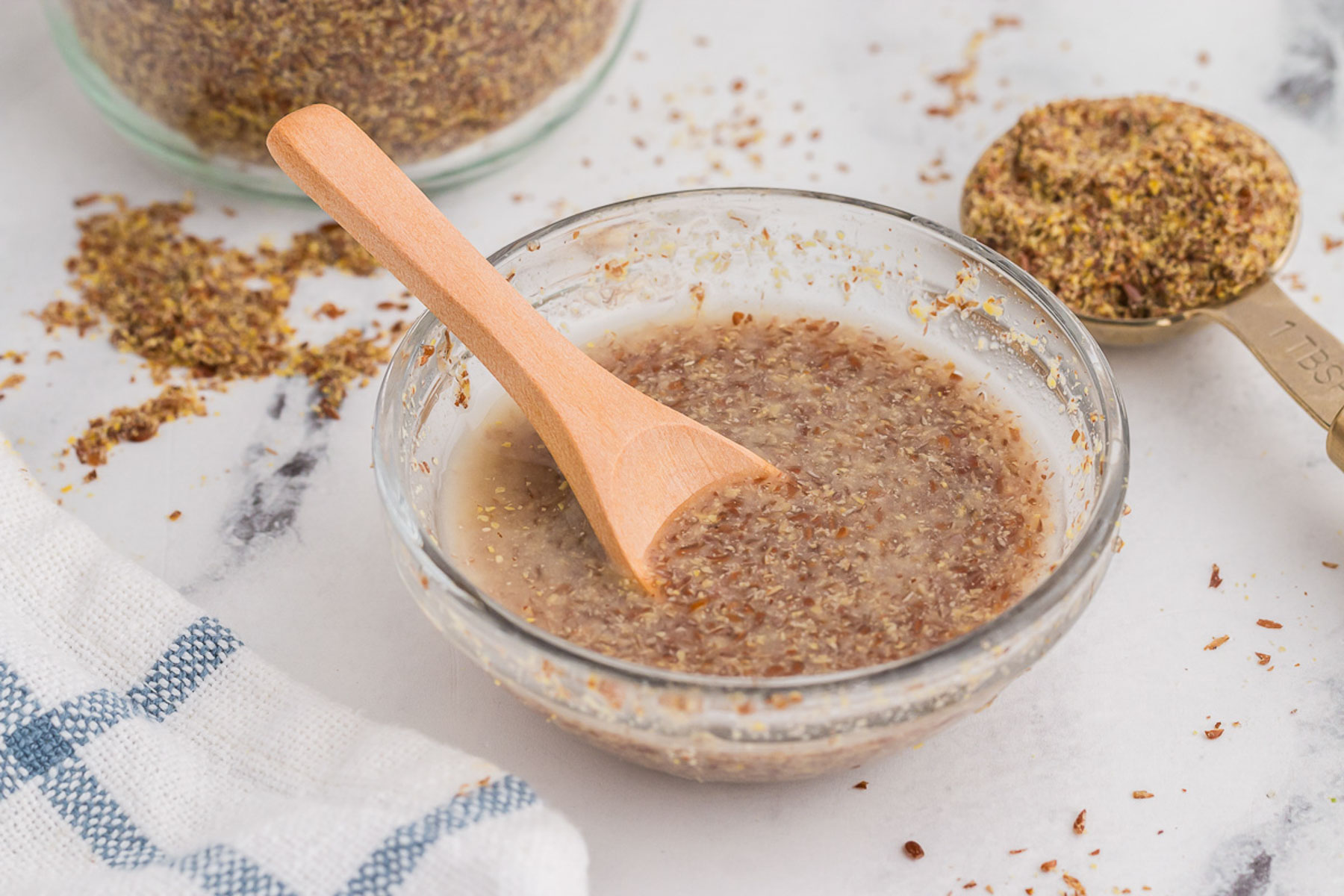 A clear bowl full of flax eggs with a wooden spoon