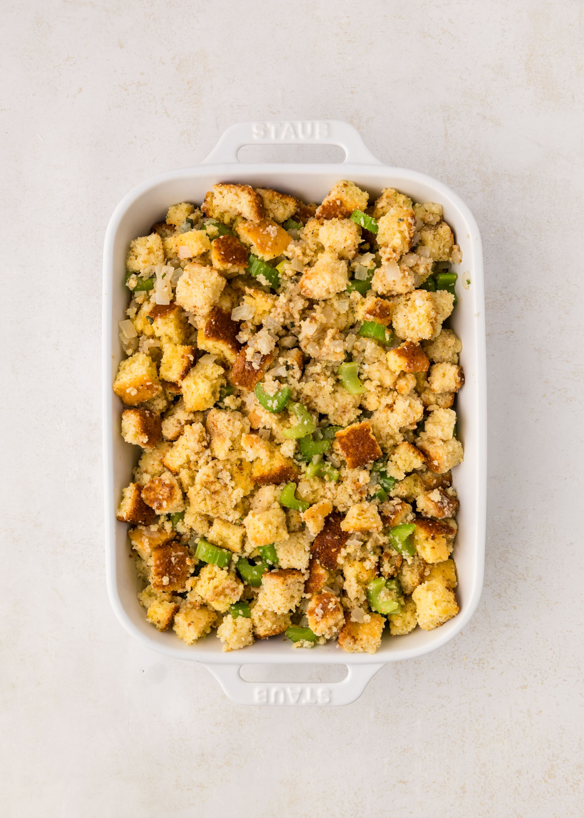 Cornbread stuffing in a white casserole dish, ready to bake.