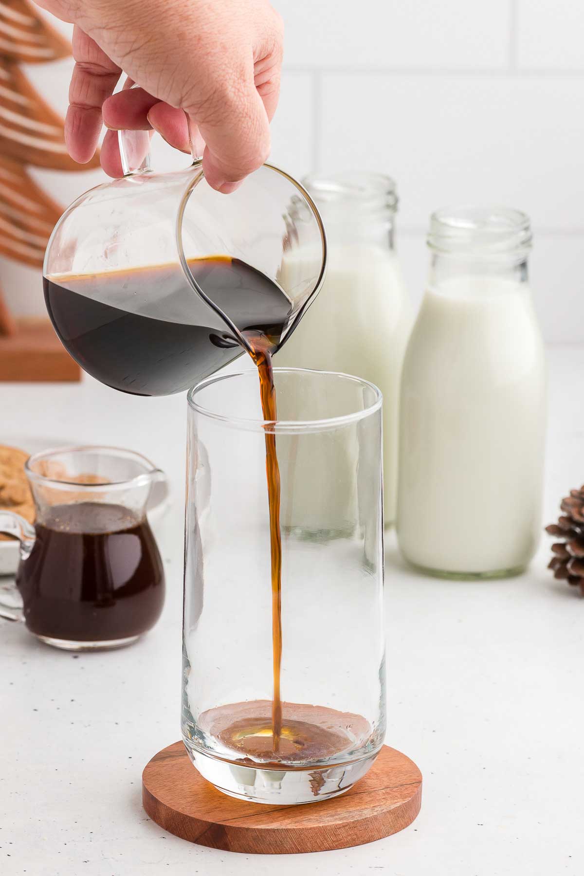 Pouring gingerbread coffee syrup into a glass for a Gingerbread Iced Latte